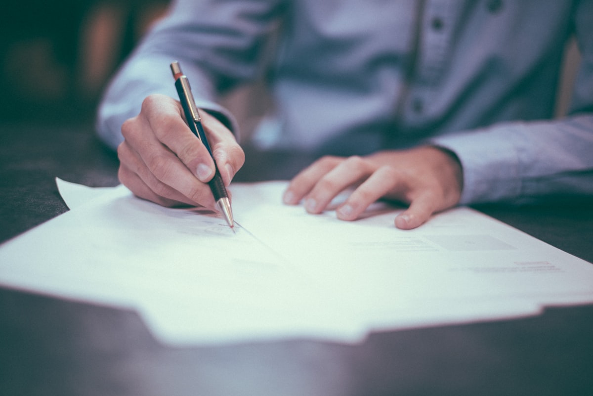 Mag je een webshop beginnen zonder KVK? Het eerlijke antwoord - Mag je een webshop beginnen zonder KVK? Het eerlijke antwoord Hand ondertekent een document met balpen